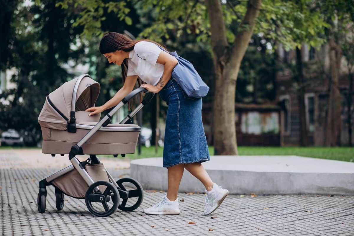 Мама гуляет с ребенком в коляске на улице 